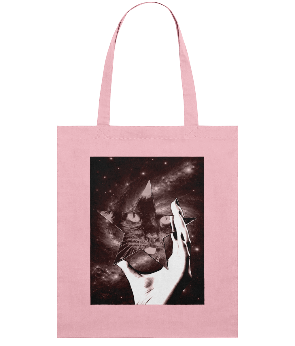 Pink tote bag with surreal art design printed on the front. The artwork features a woman's hand holding a star-shaped mirror in space, with a cat's face reflected in it.
